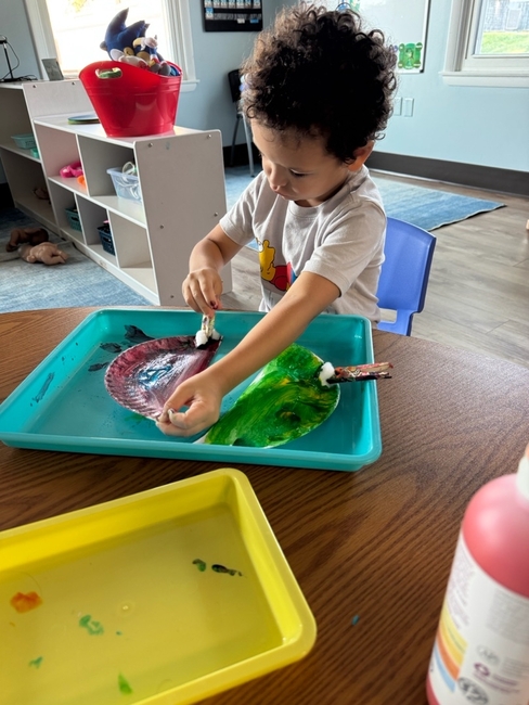 Child painting in class at Love2Learn